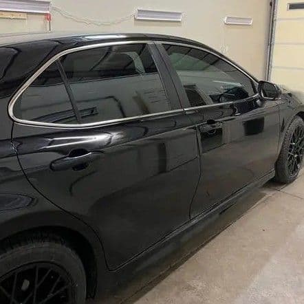 Black sedan parked in a garage with tinted windows and sleek alloy wheels.